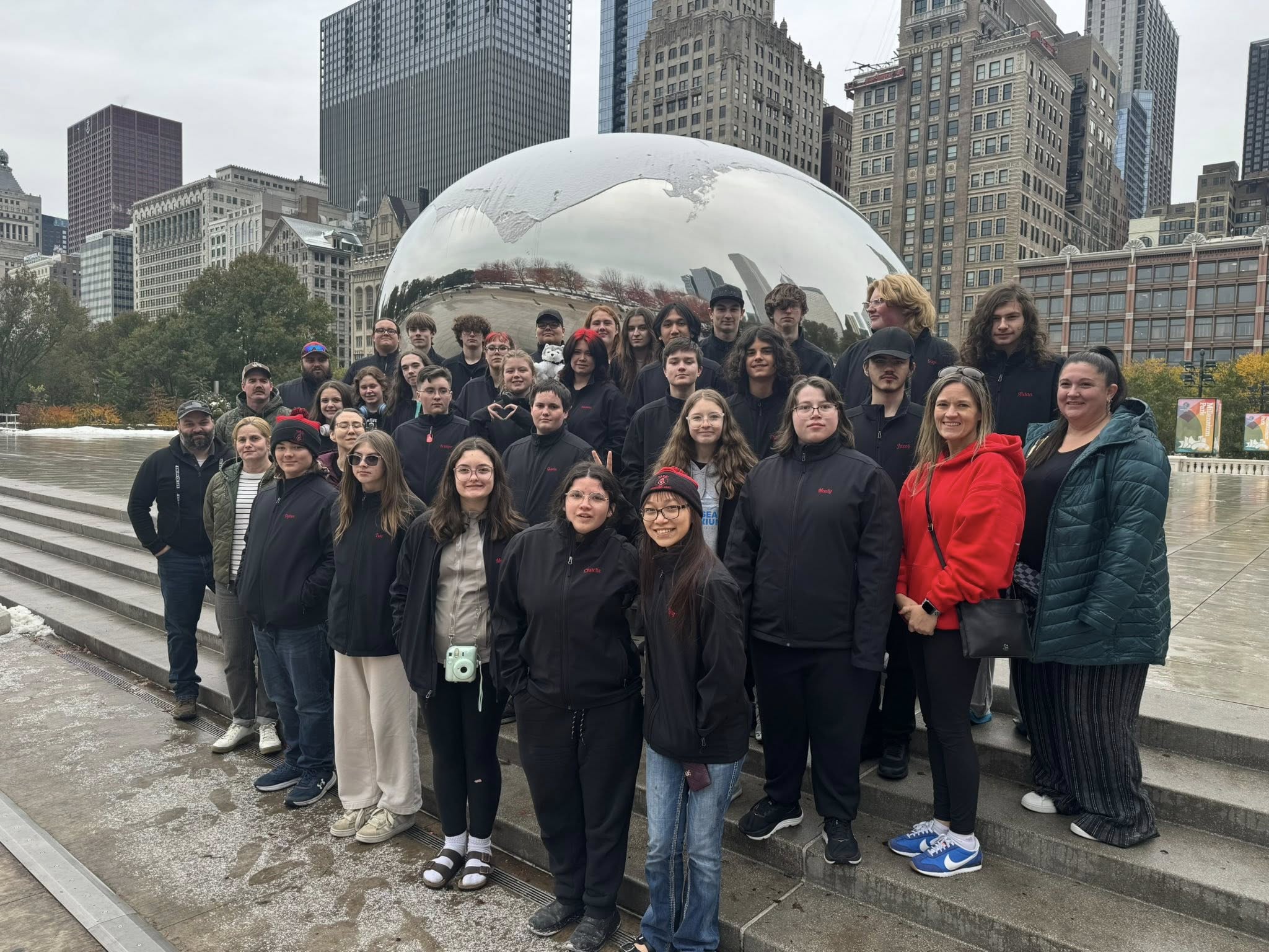 Group of students and chaperones posing for a photo in front of "The Bean"